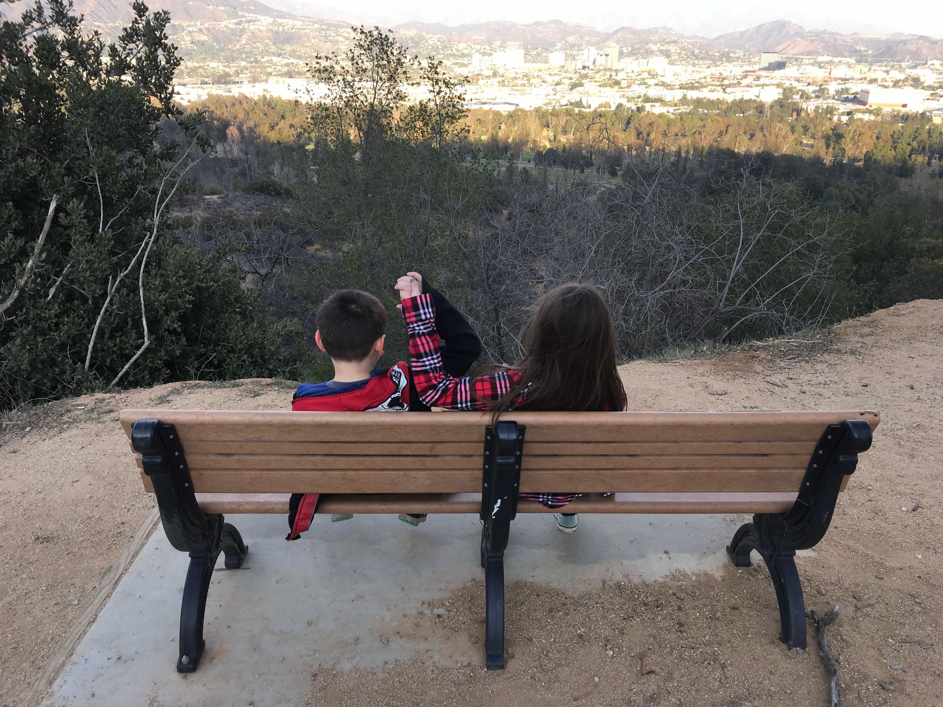 children sitting on a bench overlooking mountains